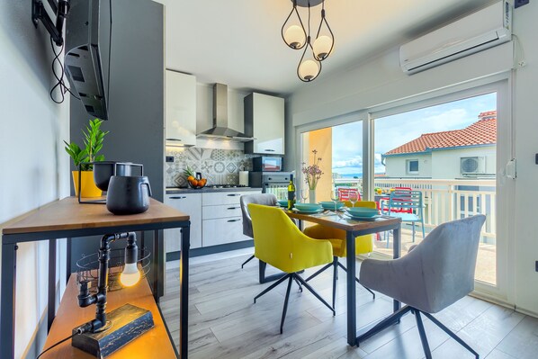 Eine moderne Küche mit Essbereich, großen Fenstern und einem Balkon mit Gartenmöbeln.
