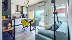 A modern kitchen with a dining area, a sofa, and a balcony with a view. - Brand new design apartment with big terrace (Kaštel Štafilić)