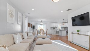A modern living room with a sofa, ottoman, and dining area with chairs.