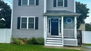 A two-story house with a front porch, a dark front door, and a small balcony.