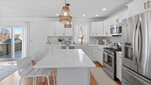 A modern kitchen with white cabinetry, stainless steel appliances, and a large island with seating.