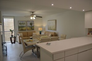 A modern kitchen with a central island, dining area with a table and chairs, a sofa, and a ceiling fan. - Coastal Island Retreat! Right off the beach! (South Padre Island)
