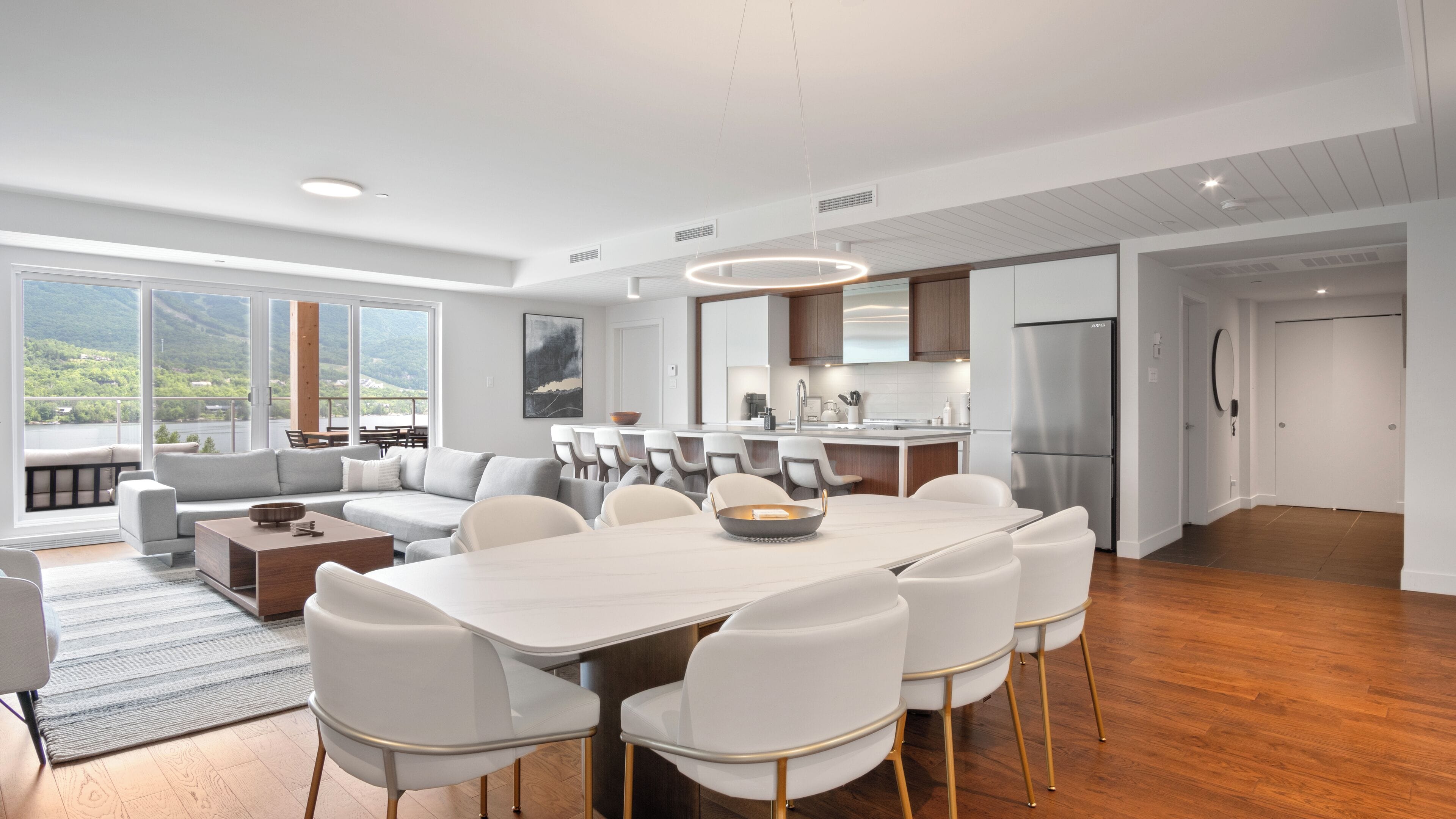 A modern kitchen with a central island, a dining area with a large table and chairs, and a seating area with a sofa and chairs.