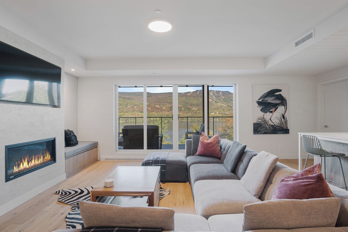 Een moderne woonkamer met een open haard, een ruime bank, een eethoek en uitzicht op de omgeving.