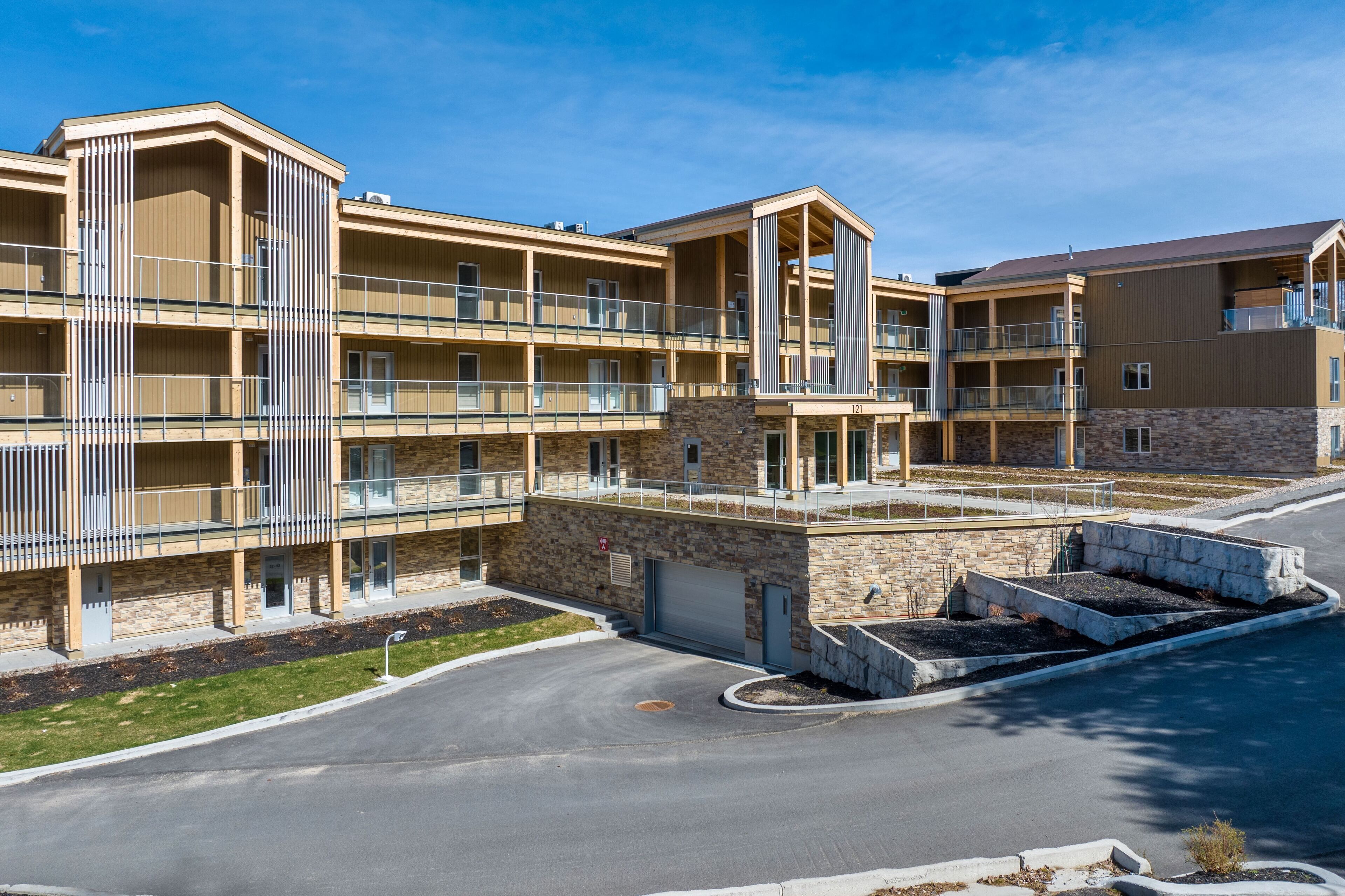 A multi-story hotel with balconies, a parking area, and a stone facade.