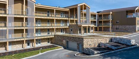 A multi-story hotel with balconies, a parking area, and a stone facade.
