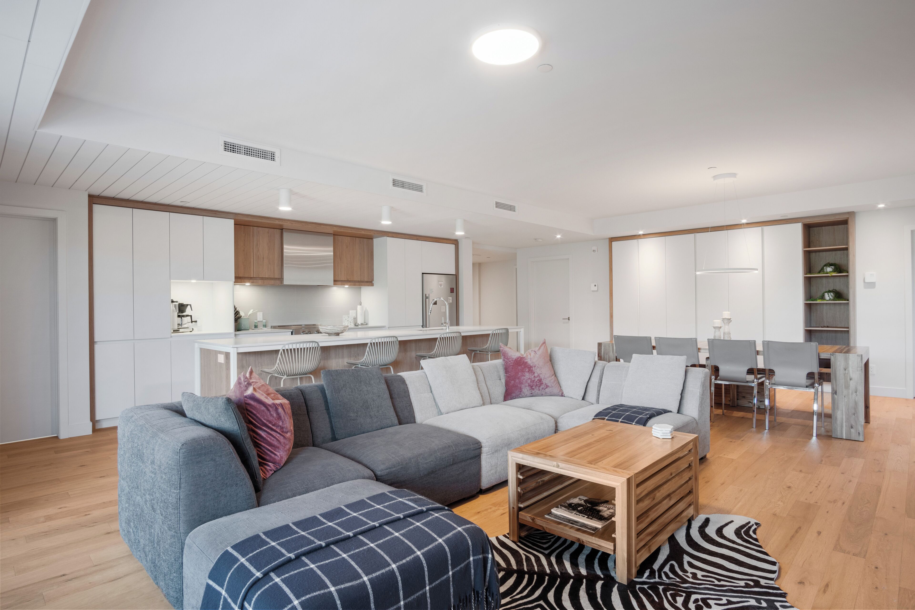 Una sala de estar moderna con un sofá modular, una mesa de centro de madera y un tapete con estampado de cebra.