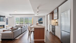 A modern kitchen with a central island, stainless steel appliances, and a large window overlooking a scenic view.