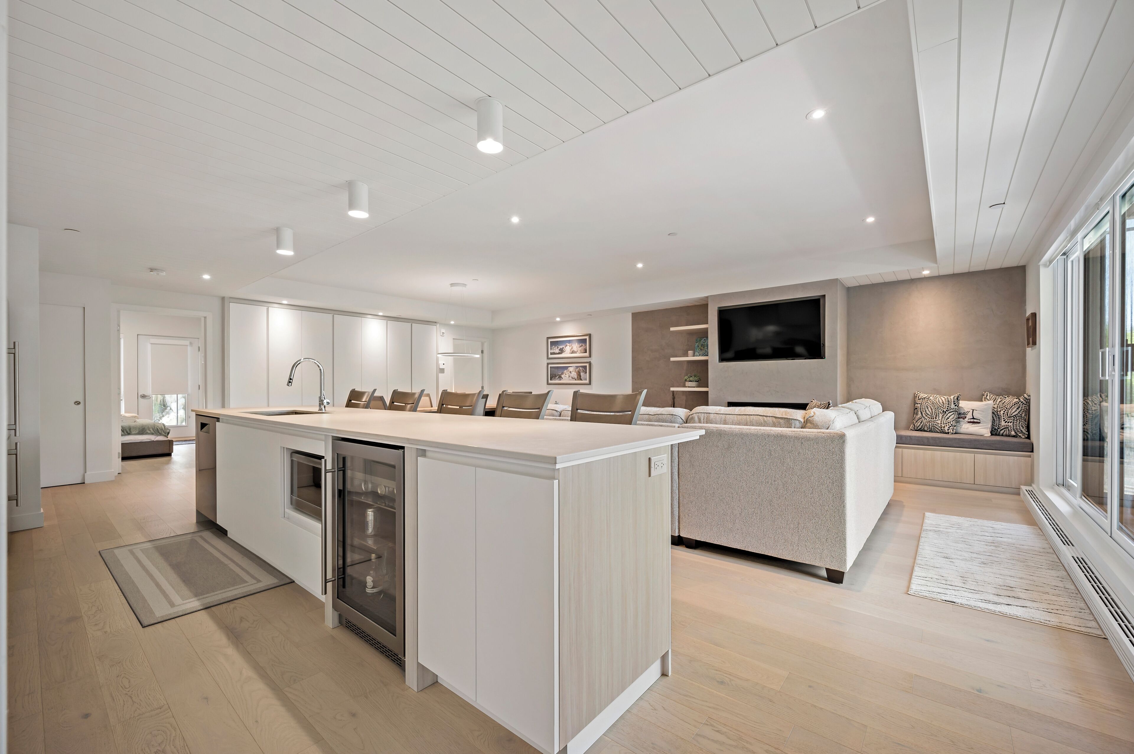 A modern kitchen with a central island, built-in appliances, and a dining area with a sofa and TV.