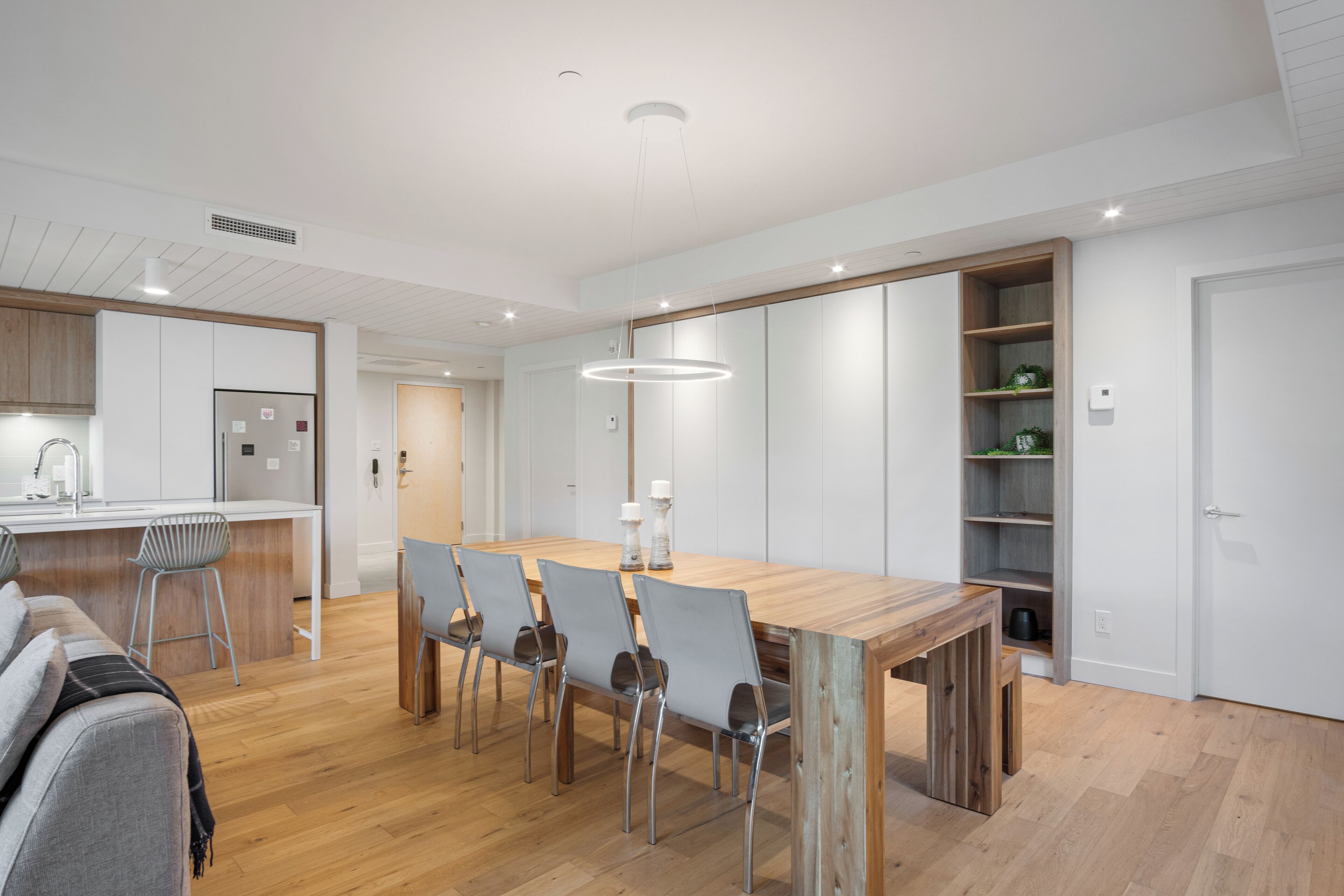 Eine moderne Küche mit Holztisch, Barhocker und einer eingebauten Vitrine mit Dekoration.