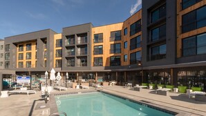 A modern building with a swimming pool, outdoor seating, and a lifeguard warning sign. - Alpine Escape Studio by Park City Vacations (Park City)