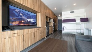 A modern kitchen with wooden cabinets, a large flat-screen TV, and a built-in microwave. - Alpine Escape Studio by Park City Vacations (Park City)