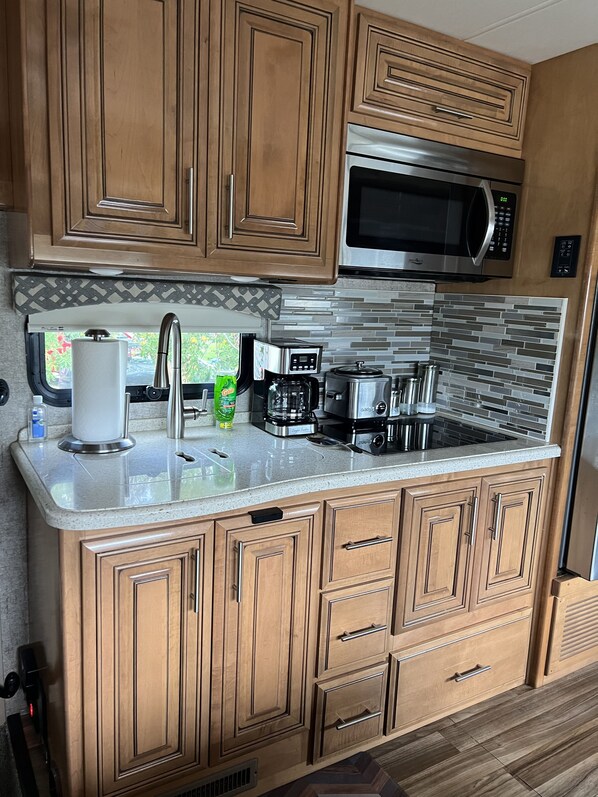 Enjoy cooking in this kitchen with a classic design, featuring a microwave, coffee maker, and sink.