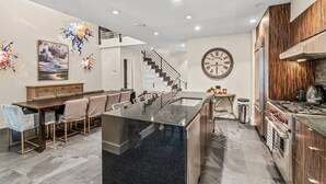 Une cuisine moderne dotée d’un îlot central, d’appareils électroménagers en acier inoxydable et d’un mur d’accent en bois.
