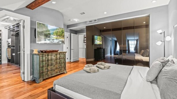 Une chambre à coucher moderne, dotée d’un grand lit, d’une commode, d’un téléviseur et offrant une vue sur un paysage montagneux.