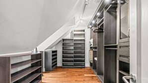 Un placard moderne doté de nombreuses étagères et de tiroirs, un plancher en bois et un escalier menant à un niveau supérieur.
