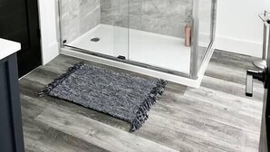 Moderni kylpyhuone, jossa on lasiseinällinen suihku, marmoriseinät ja puulattia.