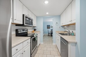 A compact kitchen with white cabinets, a built-in oven, a microwave, and a dishwasher.