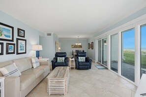 A spacious living room with a sofa, two armchairs, a coffee table, and a dining area in the background.