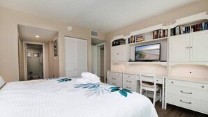 A bedroom with a bed, a desk, a chair, a television, and a bookshelf. - Perfect Beachfront Escape at Ocean House 122 (St. Augustine)