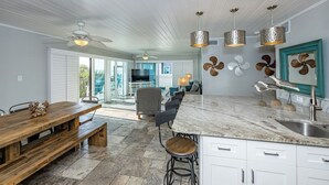 Een ruime keuken met een marmeren aanrecht, houten bankjes en een groot eiland met een spoelbak.