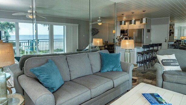 Een woonkamer met een grijze bank, een salontafel en uitzicht op de oceaan.