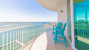 A balcony with a view of the ocean and a distant cityscape.
