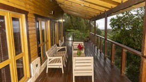 A wooden deck with a wooden bench and a table with a vase of flowers. - Loma de Sion (San Francisco de Macorís)