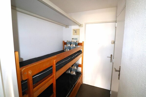 A bunk bed with a geometric-patterned pillow, a white door, and a small framed picture on the wall.