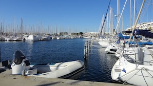 Una marina con diverse imbarcazioni ormeggiate, un cielo azzurro limpido e una superficie d'acqua calma.