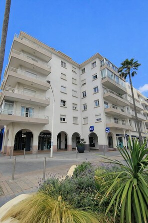 A multi-story hotel with balconies, a central courtyard, and a sign indicating a location. - 2-Bedroom Apartment Close to the Beach, Shops, Entertainment  5CDUSUD1 (CANET PLAGE)