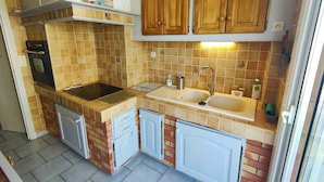 A compact kitchen with a stove, sink, and cabinets. - 2-Bedroom Apartment Close to the Beach, Shops, Entertainment  5CDUSUD1 (CANET PLAGE)