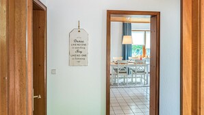Een gang die leidt naar een eetruimte, met een houten deurkozijn en een bord aan de muur.