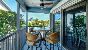 Enjoy the serene views of palm trees and buildings from this balcony, complete with a glass table and four comfortable chairs.