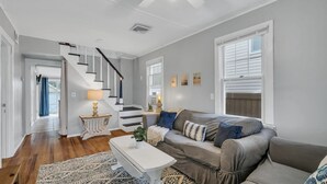 A spacious living room with a grey sofa, a white coffee table, and a staircase leading to an upper level. - Beach house! Sleeps 8, off street parking (Manasquan)