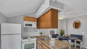 A kitchen with white appliances, wooden cabinets, a granite countertop, a dining table with chairs, and a decorative mirror. - Beach house! Sleeps 8, off street parking (Manasquan)