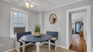 A dining room with a round table, two chairs, a ceiling fan, a mirror, and a window with blinds. - Beach house! Sleeps 8, off street parking (Manasquan)