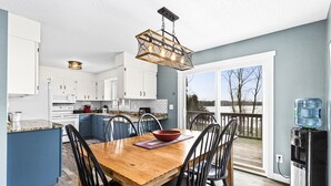 A modern kitchen with white cabinets, a wooden dining table, and a water dispenser.