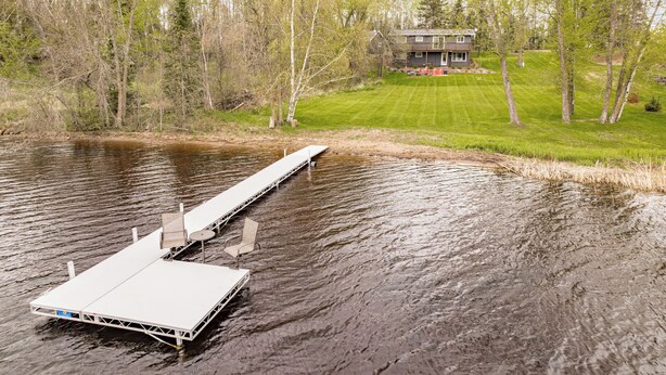 A dock extending into a lake with a house in the background.