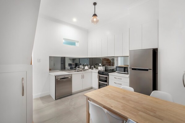 Enjoy cooking in this well-equipped kitchen with a stainless steel refrigerator, oven, and dining table.