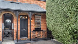A brick building with a black door, a window with blinds, and a black wrought iron gate. - Brisbane Terrace - Hobart Inner City - Free Parking - Free WIFI (Hobart)