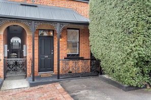 Traditional brick building with a black metal entrance and a small window.