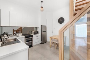 Modern kitchen with a large island, sink, and stainless steel appliances, including a refrigerator, microwave, and oven.