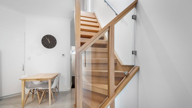 A modern interior with a wooden staircase, a dining area with chairs, and a wall clock. - Brisbane Terrace - Hobart Inner City - Free Parking - Free WIFI (Hobart)