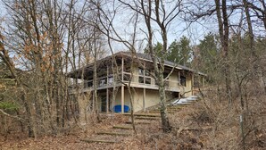 Un bâtiment à deux étages doté d’un balcon, entouré d’arbres et de végétation luxuriante.