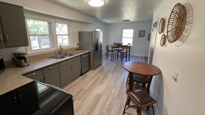 A modern kitchen with a built-in oven, a refrigerator, and a dining area with a table and chairs.