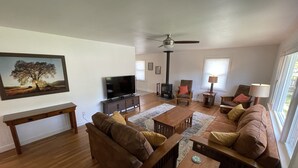 A living room with a sofa, coffee table, TV, fireplace, and a painting of a tree.