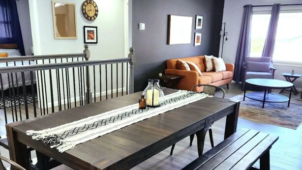 A modern living room with a dining table, benches, and a sofa.