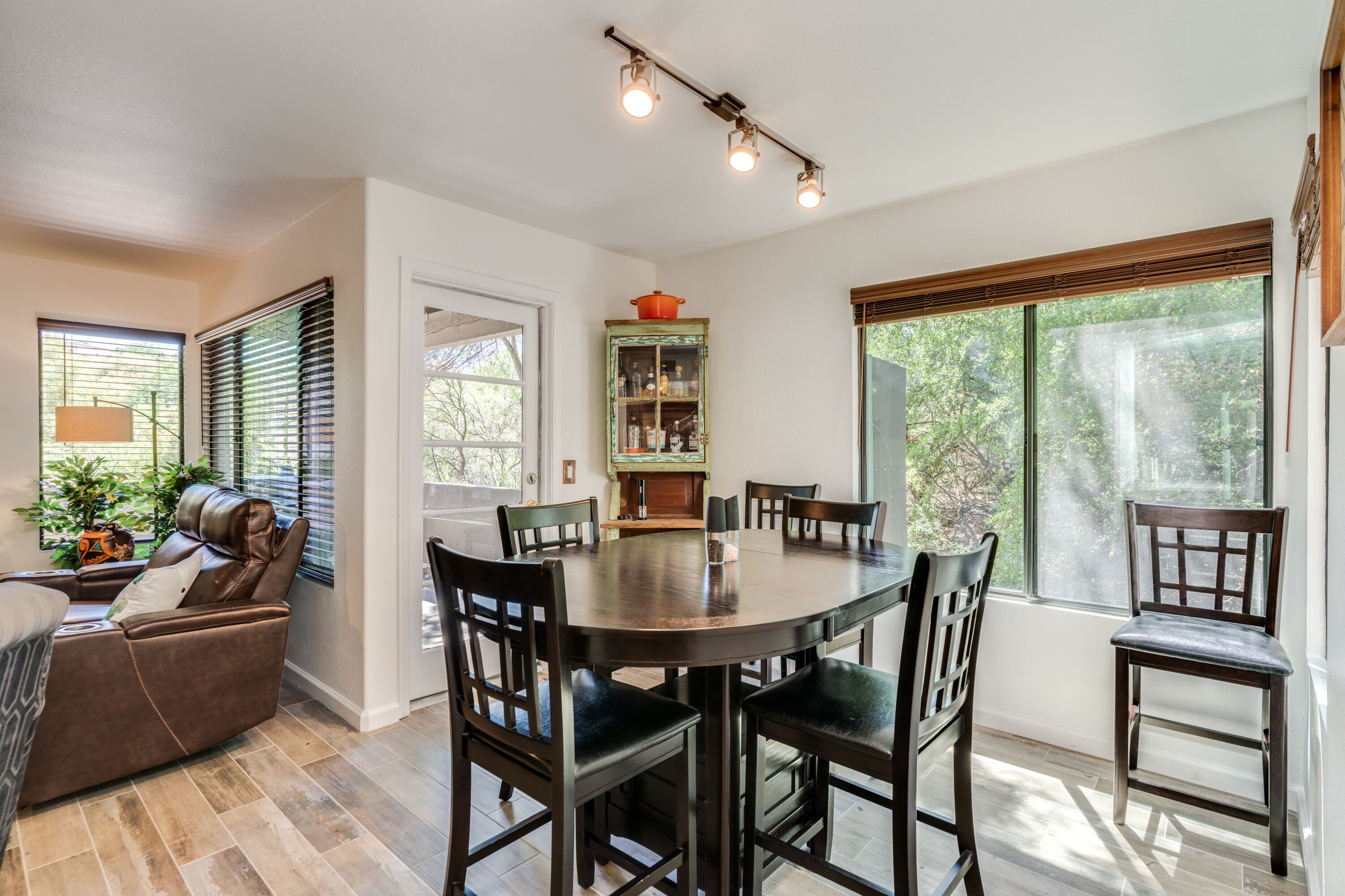 A dining area with a round table, six chairs, and a cabinet with glass doors.