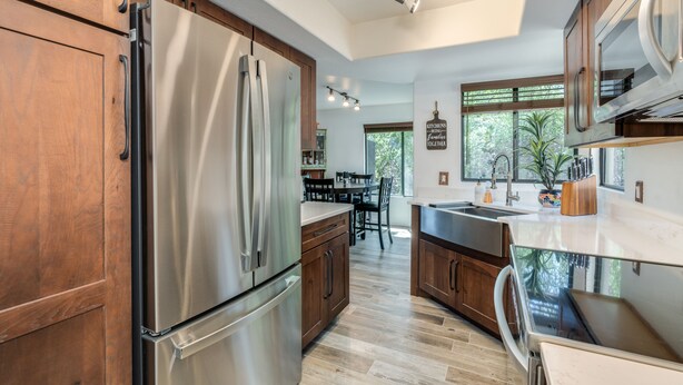 A modern kitchen with stainless steel appliances, wooden cabinets, and a large window providing natural light. - Casa de la Paloma -  Peaceful Golf Course Luxury Retreat (Tucson)
